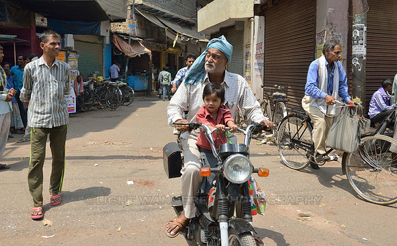 Small boy sitting with grandpa on a moped