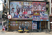 Fruit hawkers sitting beneath movie posters