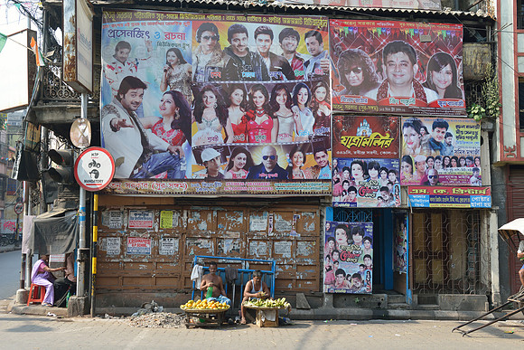 Fruit hawkers sitting beneath movie posters
