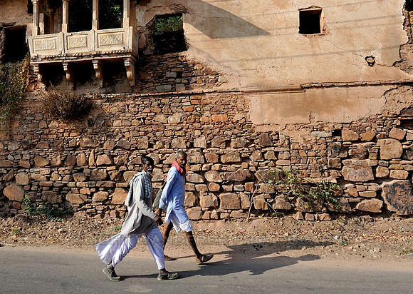 Men walking past crumbling stone building
