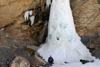 Hiker in front of frozen waterfall