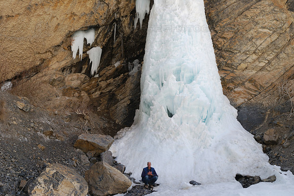 Hiker in front of frozen waterfall