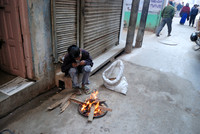Boy tending fire in alley