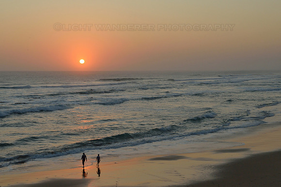 Two people on the beach at sunset