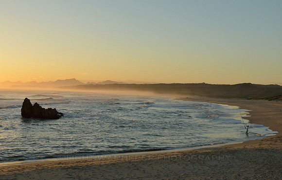 Man fishing on the beach at sunset time
